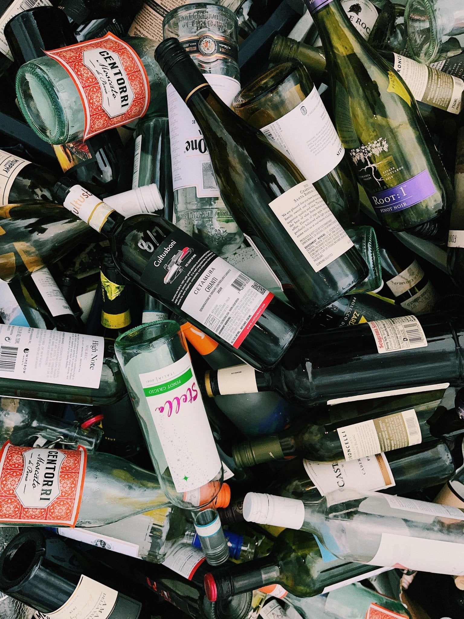 Piles of discarded wine bottles in a recycling bin, showing the volume and variety of locally collected glass.