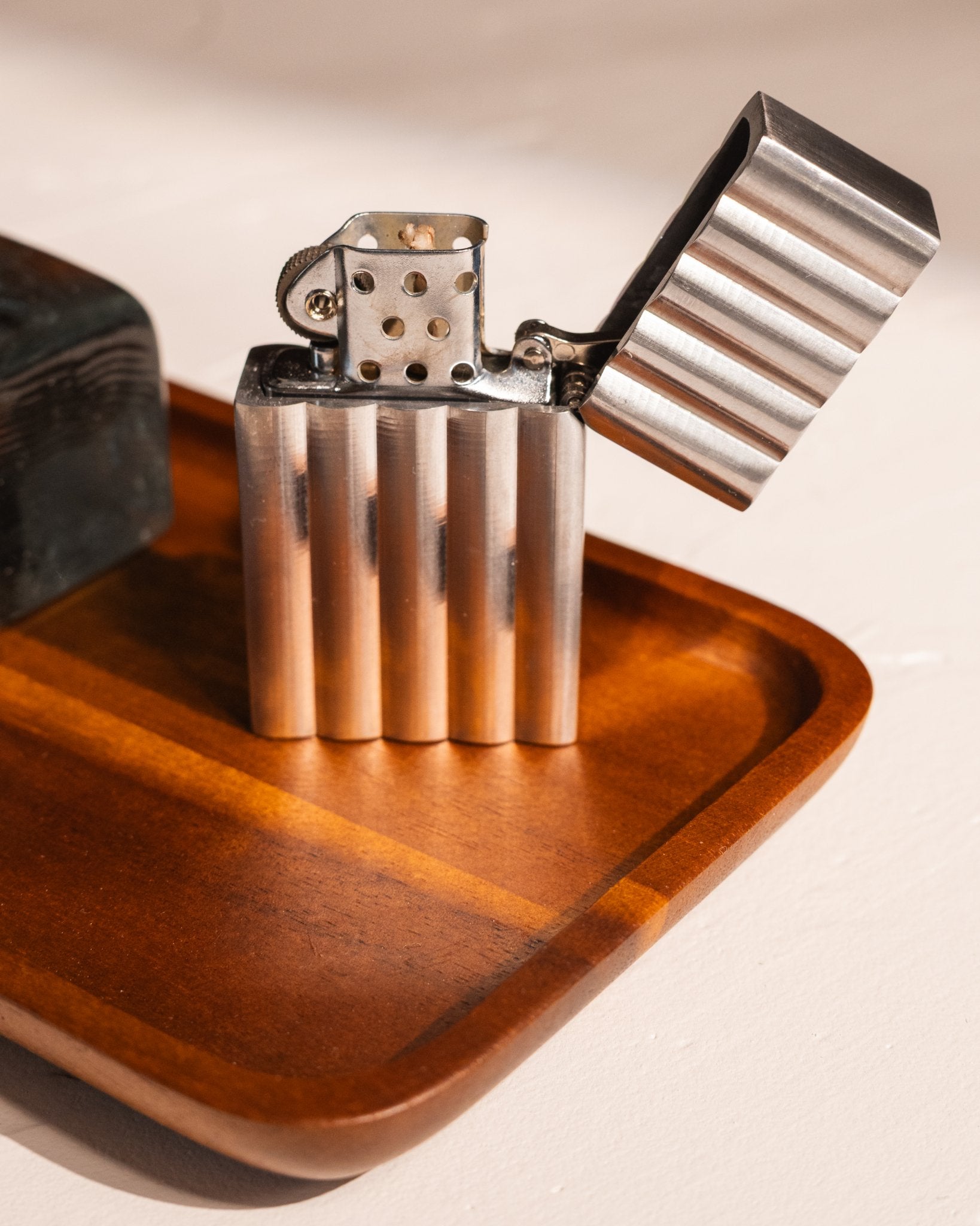 Aluminum wave lighter on a wooden acacia tray with a neutral background