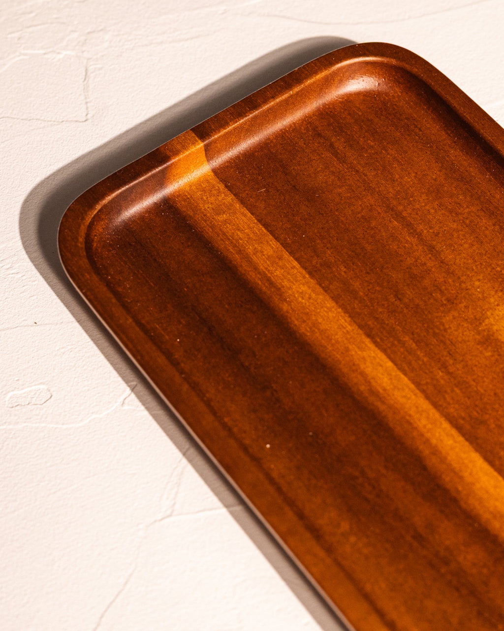 Close-up of acacia wood tray showing amber-brown grain and rounded edges