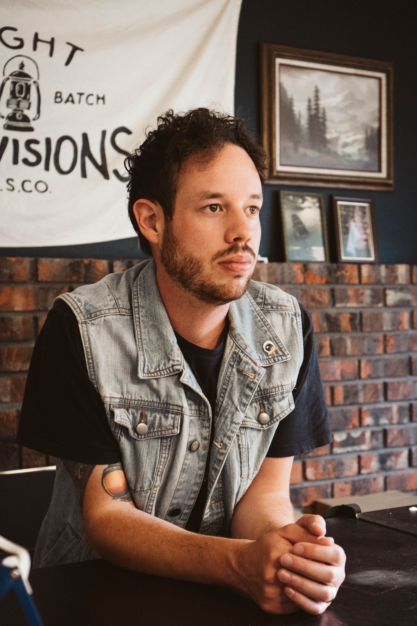 Brett Owens, founder of Light Provisions seated in the studio with the original Light Provisions banner in the background.