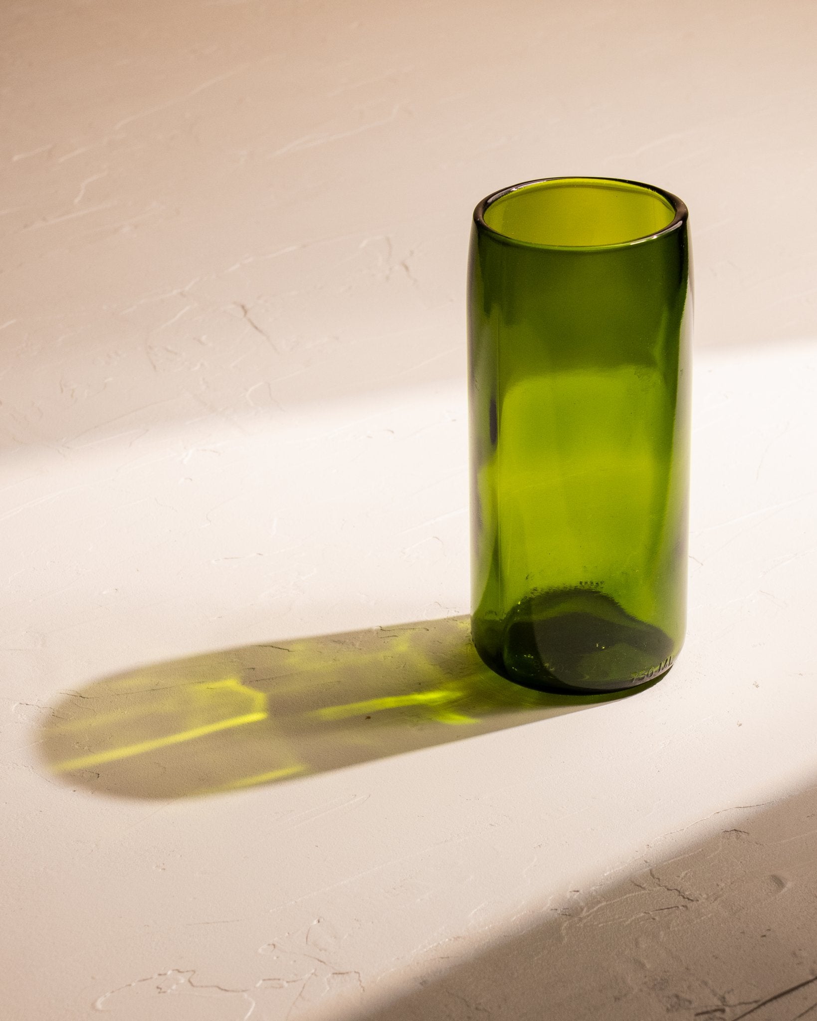 Champagne green recycled wine bottle incense vase casting a yellow-green shadow.
