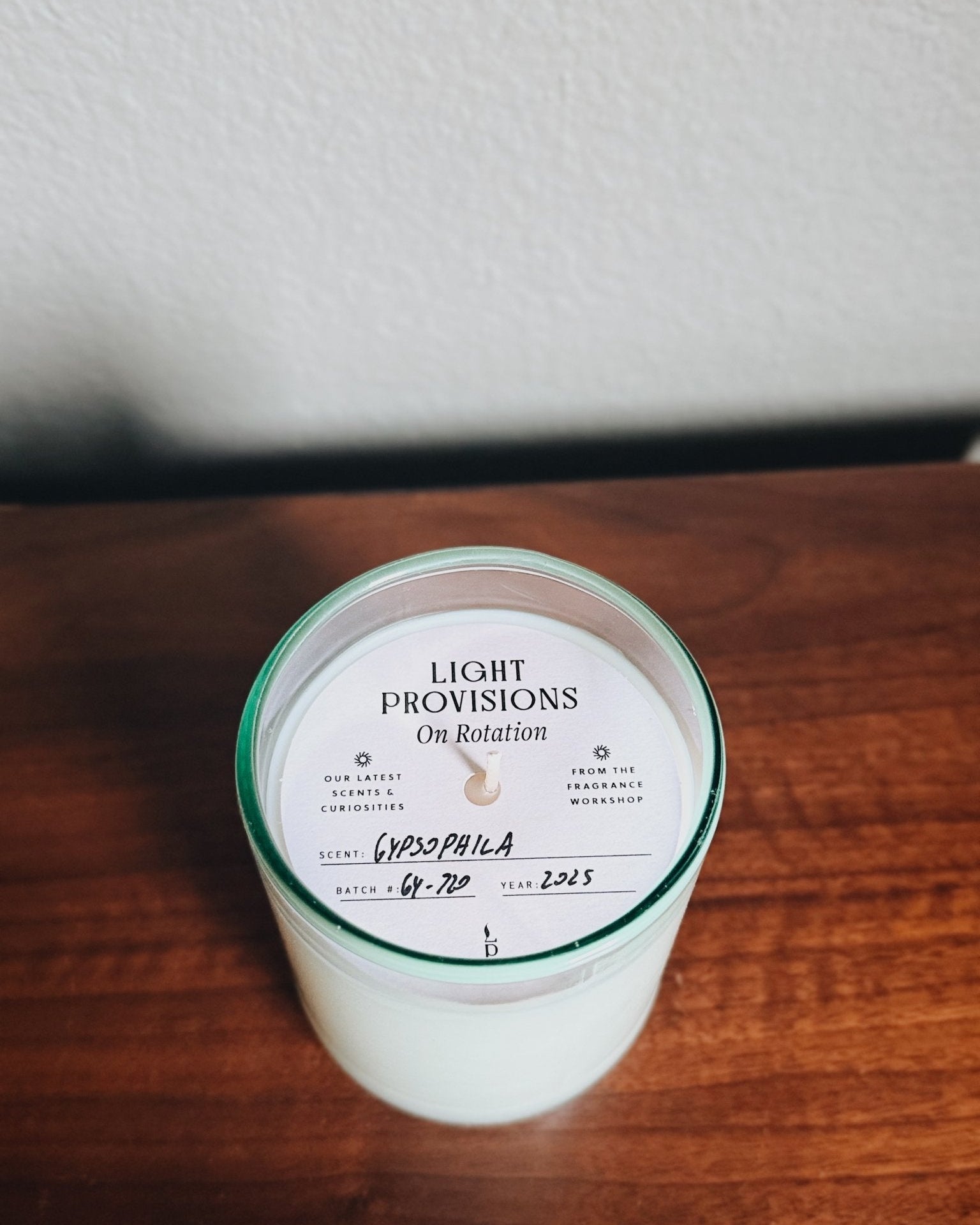 Hand-poured Gypsophila candle in aqua recycled glass with labeled dust cover from Light Provisions On Rotation collection.