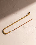 Brass hook incense holder with incense stick on textured surface