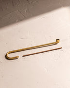 Close-up of curved brass-finished incense holder with incense stick
