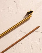 Close-up of brass hook incense holder clip and incense stick