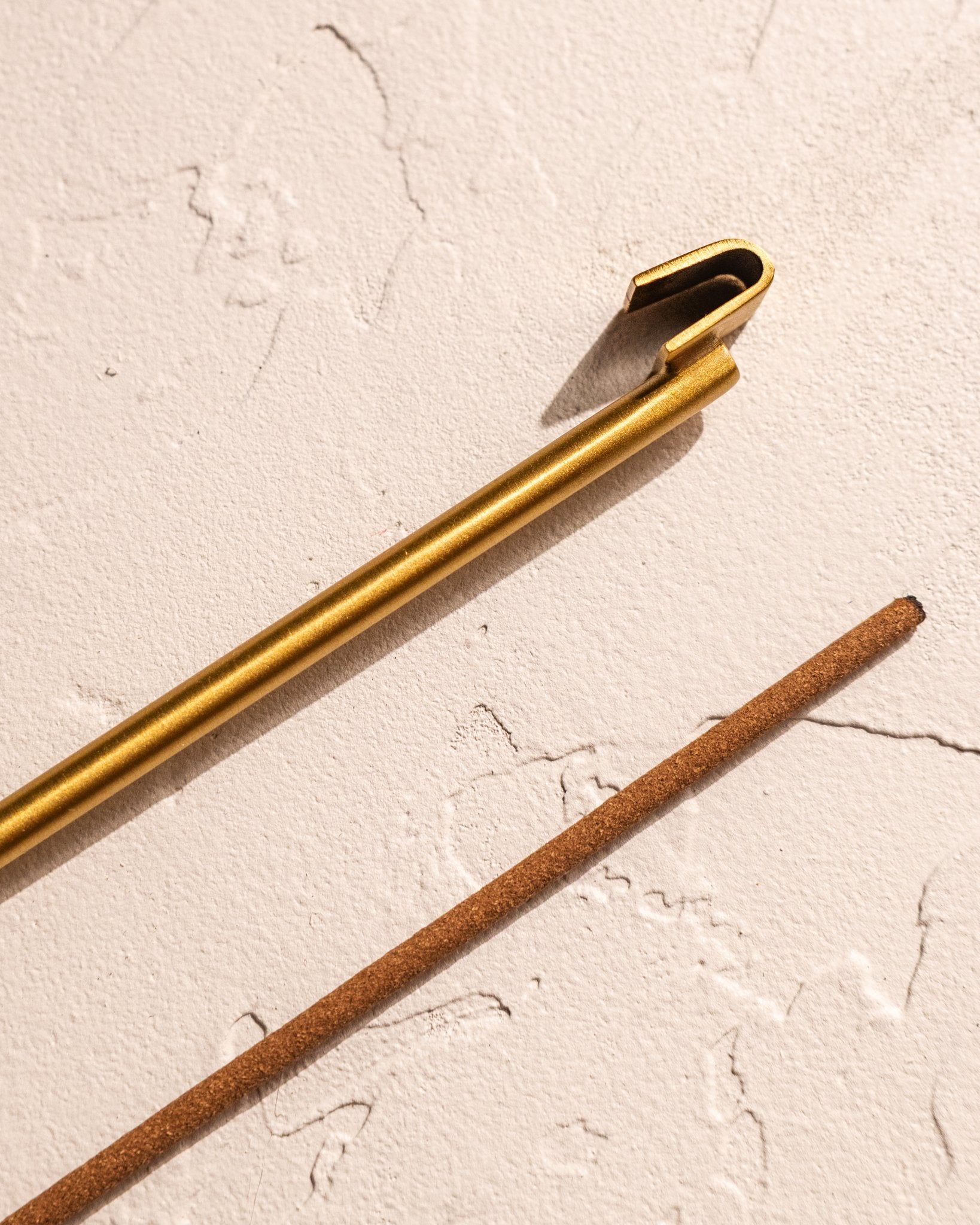 Close-up of brass hook incense holder clip and incense stick