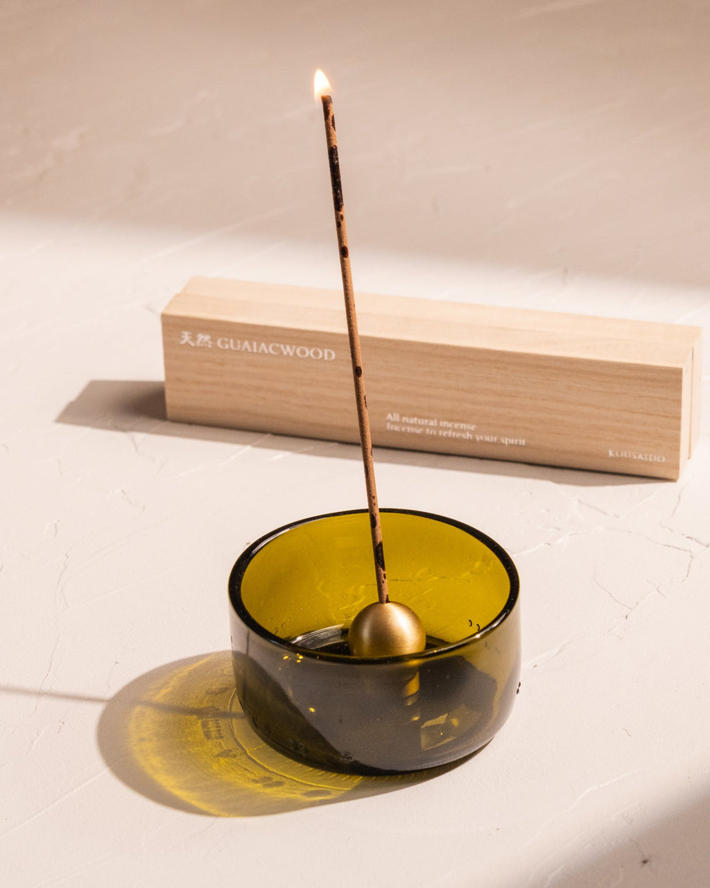 Kousaido Guaiac Wood incense burning in brass holder with wood box nearby