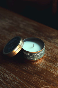 Open tin with lid tilted back; unlit white wax and centered wick; angled view on warm wood grain in soft shadow.