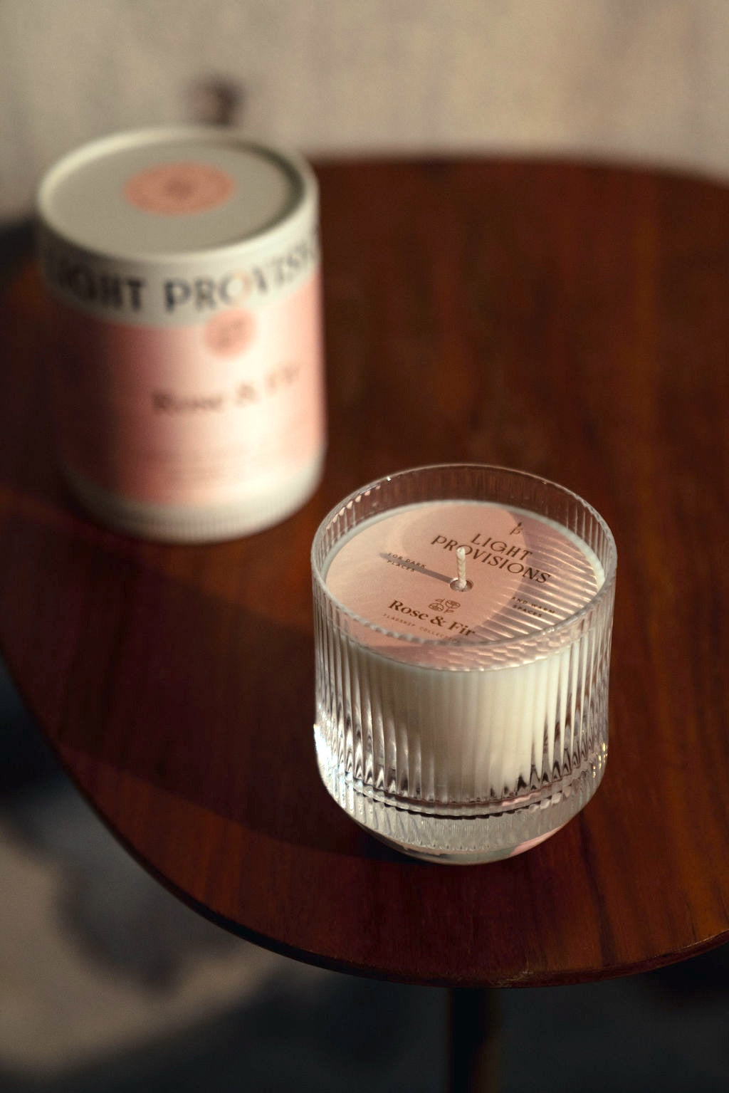 Rose & Fir candle in rippled glass jar next to matching tube packaging on wooden table