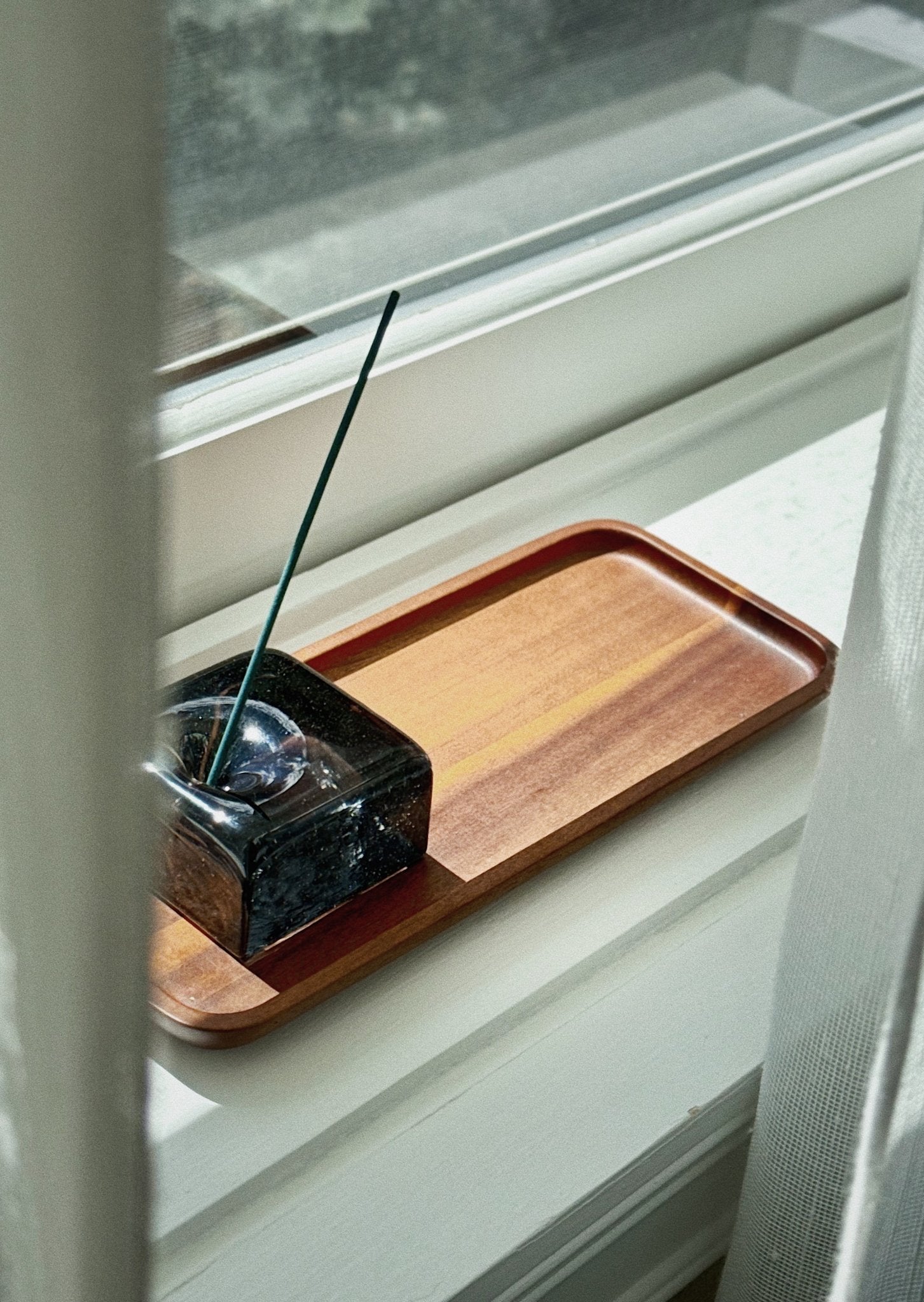 black glass incense holder on teakwood tray