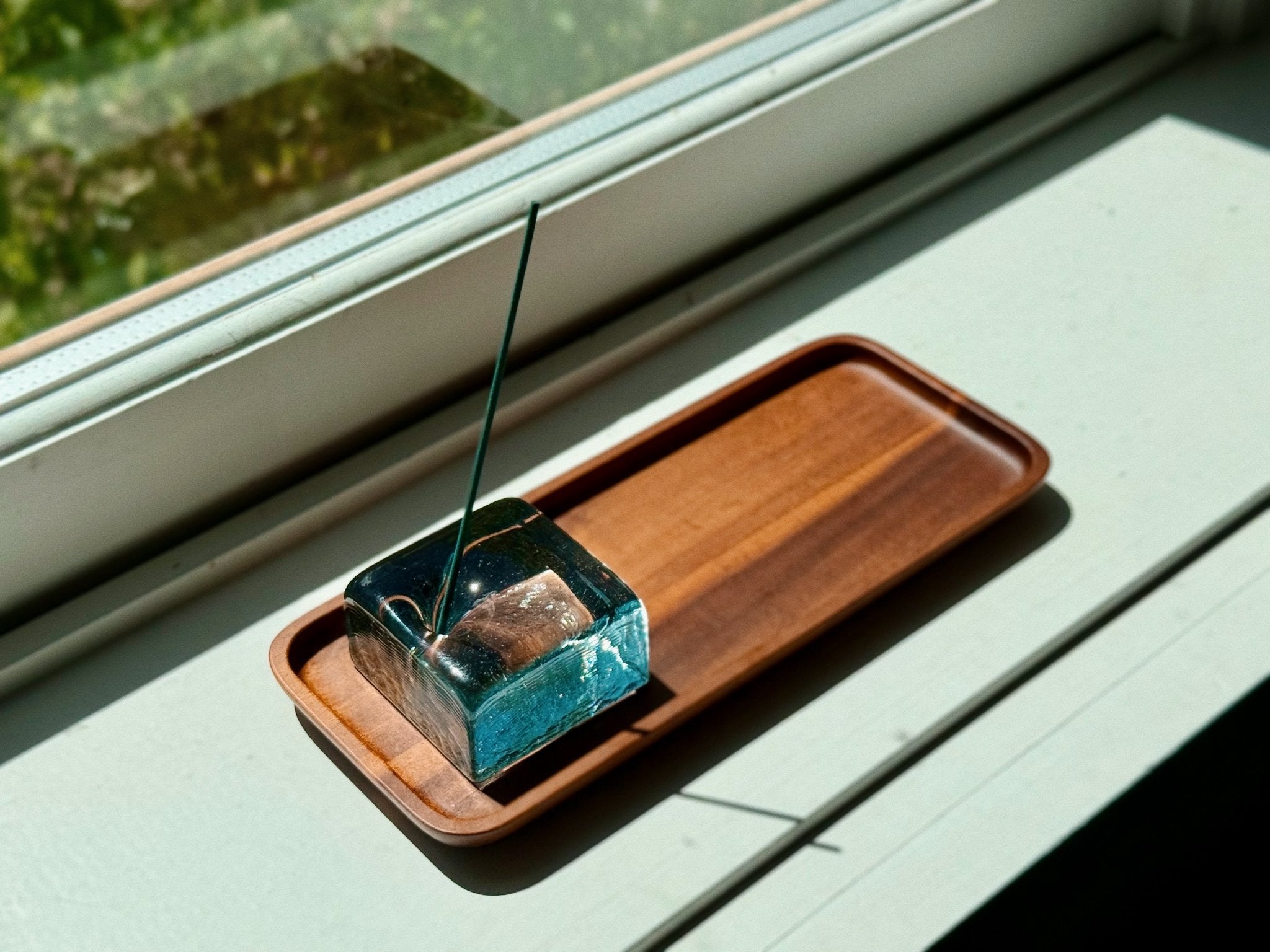 Blue recycled glass incense holder by IYE on teakwood tray on window ledge