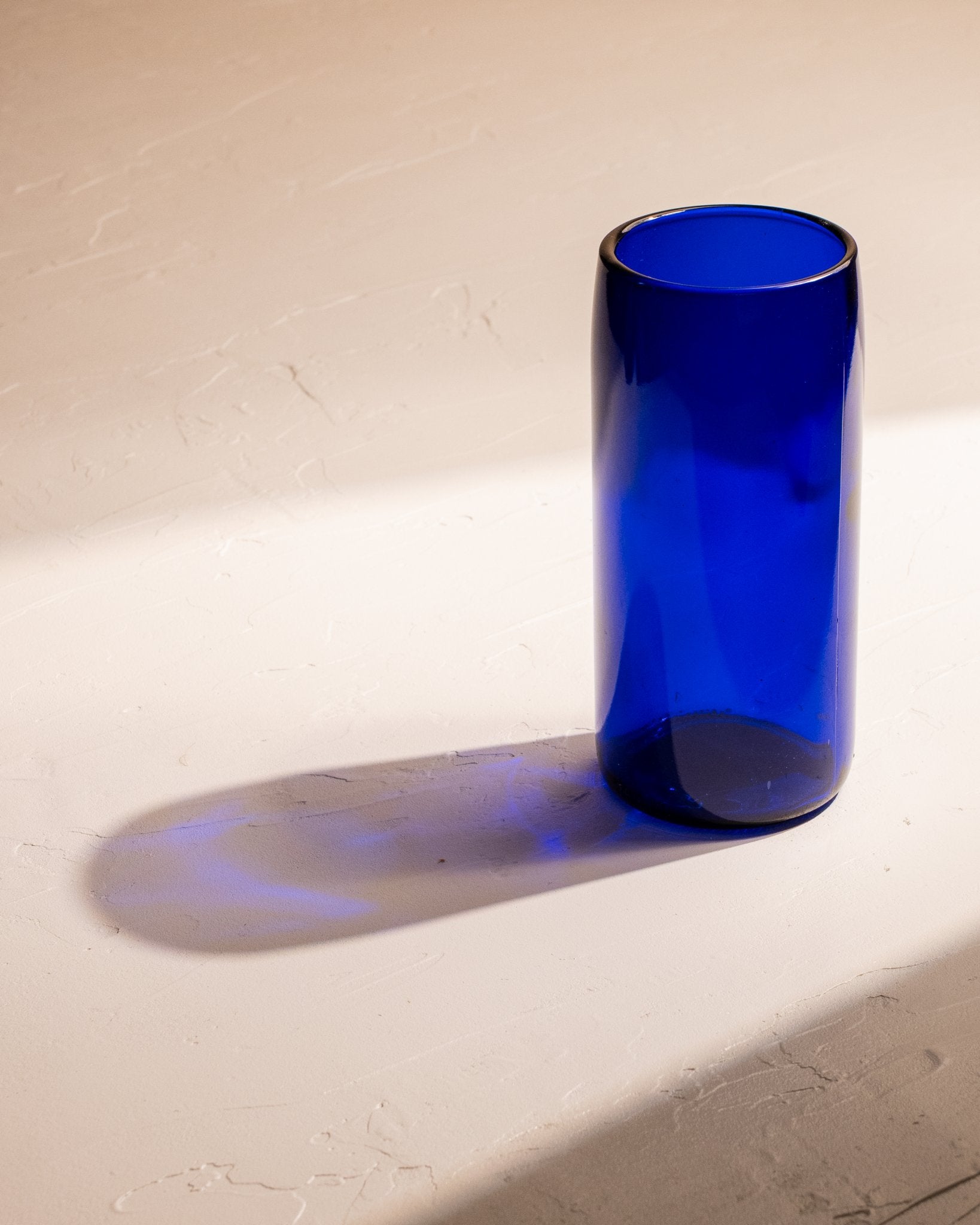 Cobalt blue recycled wine bottle incense vase casting a deep blue shadow.