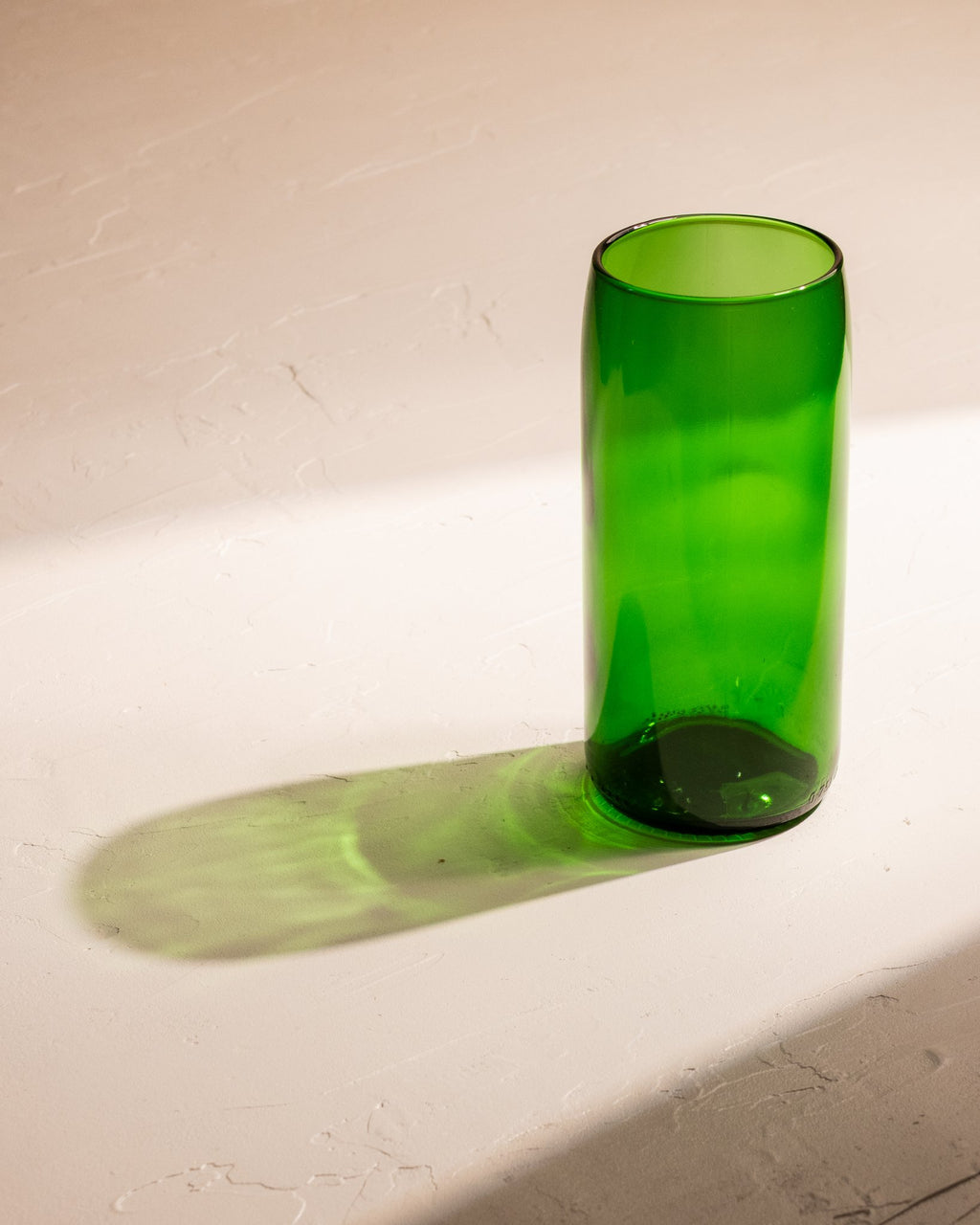 Emerald Green  recycled wine bottle incense vase casting a vivid green shadow.