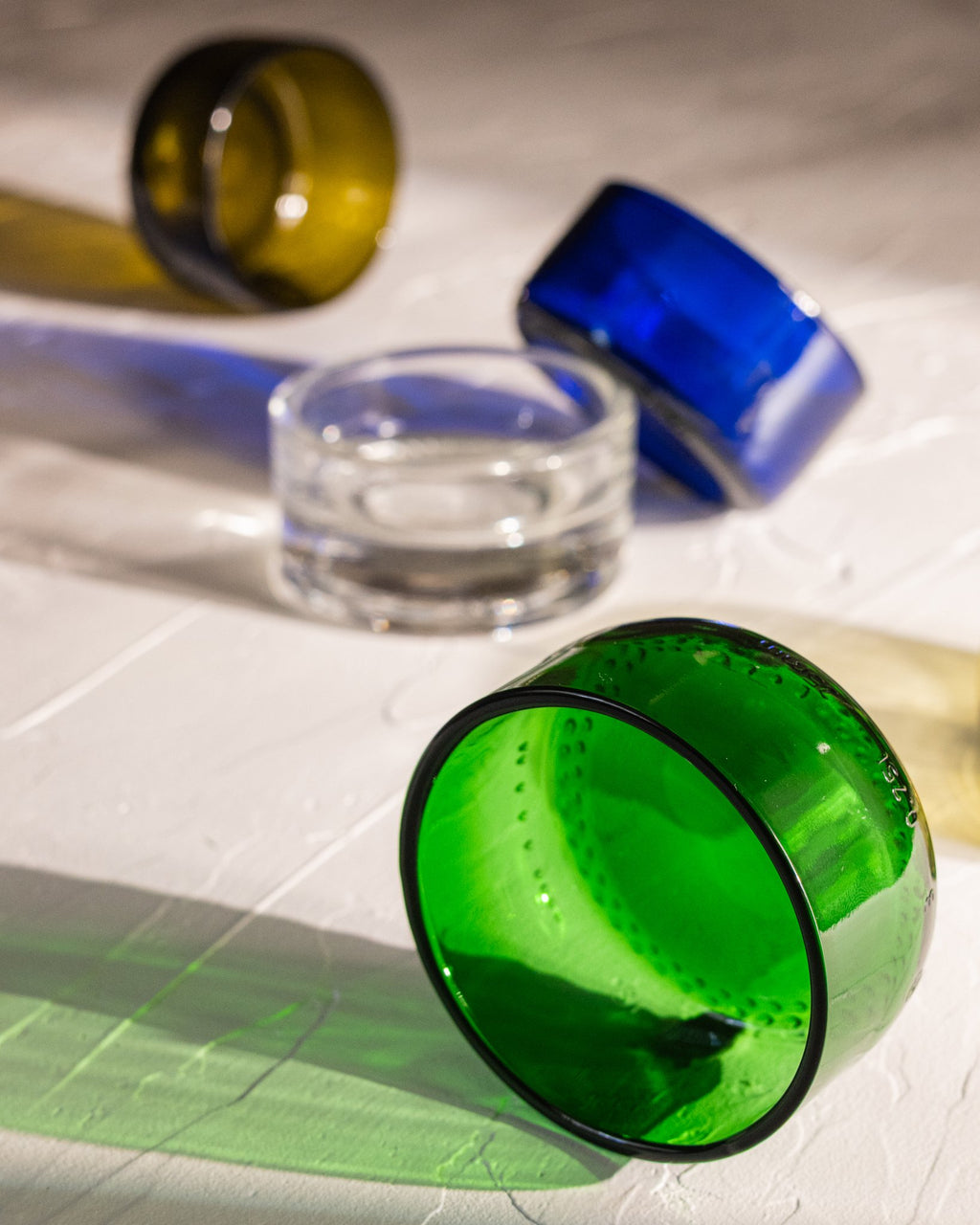 Reclaimed bottle glass dishes in blue, green, amber, olive, and clear, with green in the focal point