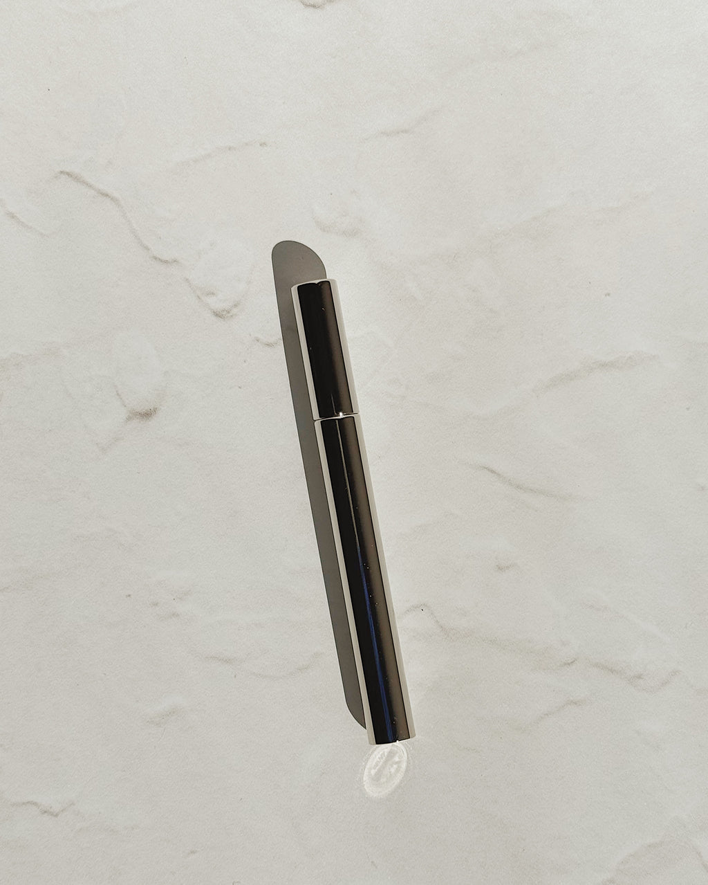 Black Tsubota Pearl Sigaretta stick lighter with its cap on, resting on a pale textured surface.