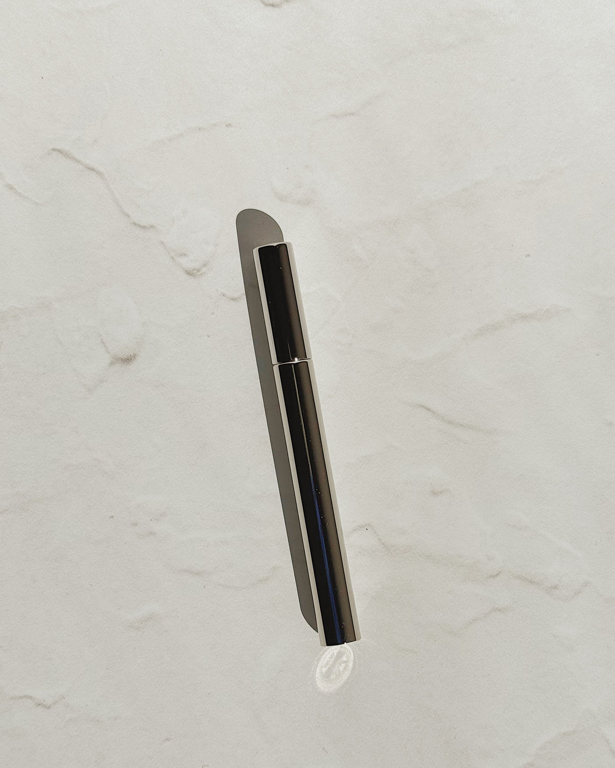 Black Tsubota Pearl Sigaretta stick lighter with its cap on, resting on a pale textured surface.
