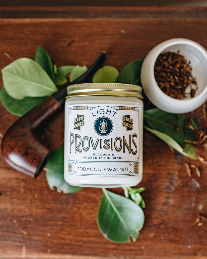Jar of Tobacco Walnut candle on wooden surface with leaves and a tobacco pipe