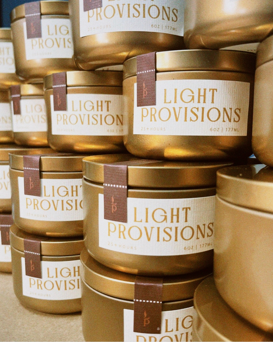 stack of Tobacco Walnut candles in gold travel tins with textured label