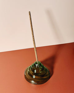 Incense stick in a green holder on a red and beige background