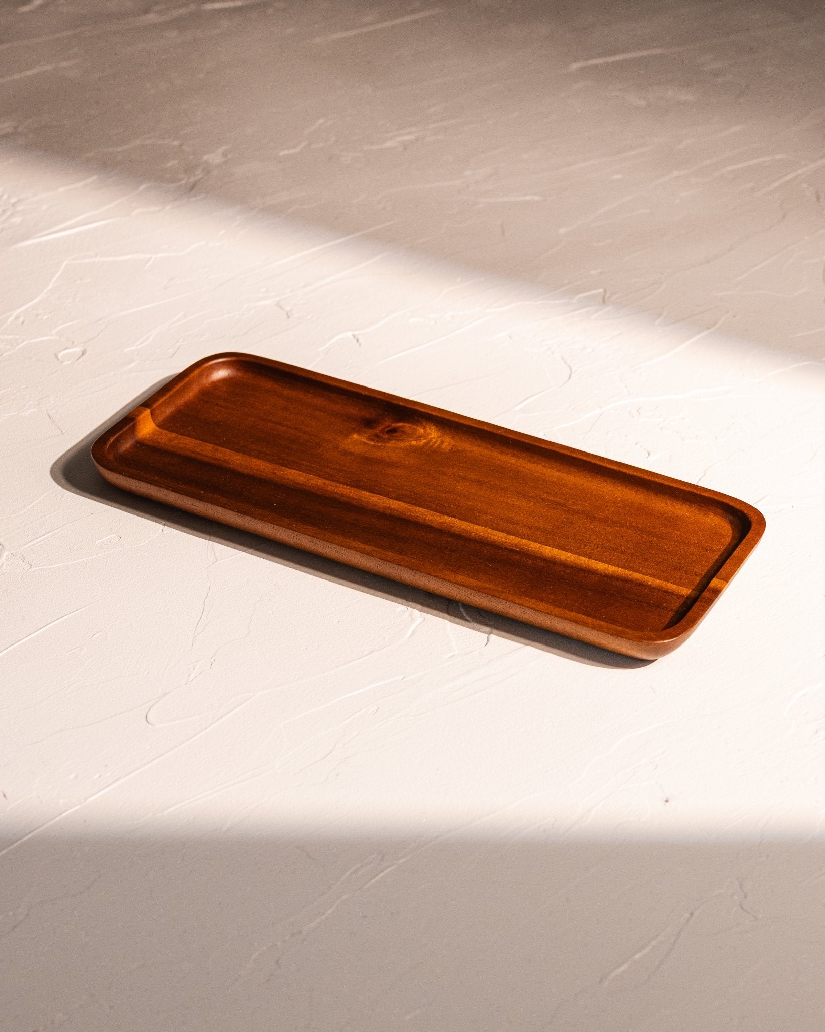 Acacia wood tray with warm lacquered finish and visible natural grain