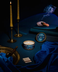 Light Provisions Autumn Twilight candles glass tumbler and travel tin with blue velvet, brass candlesticks, books, and smudge