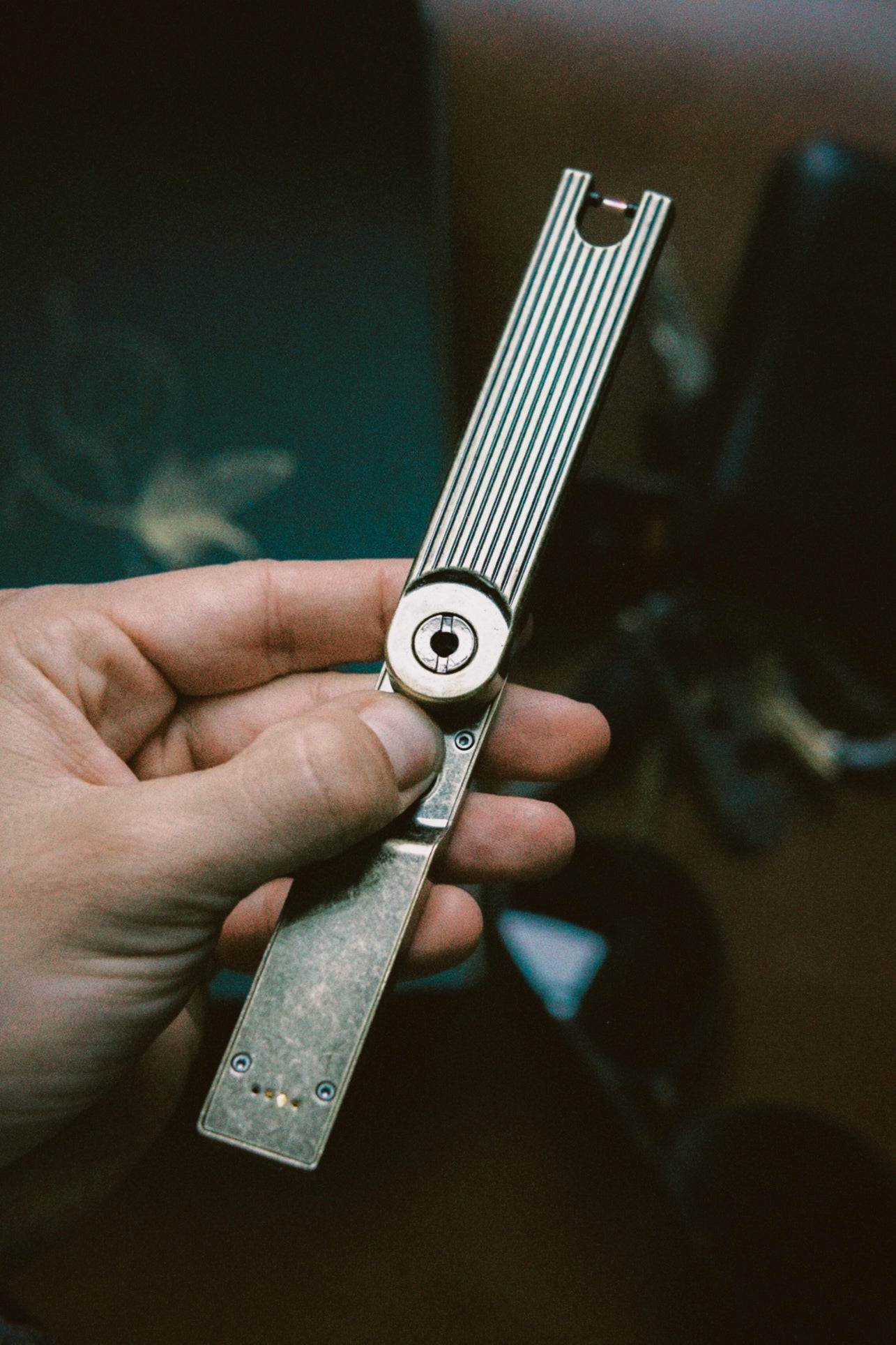 Hand holding a metallic folding arc lighter by Barebones Living with a blurred background