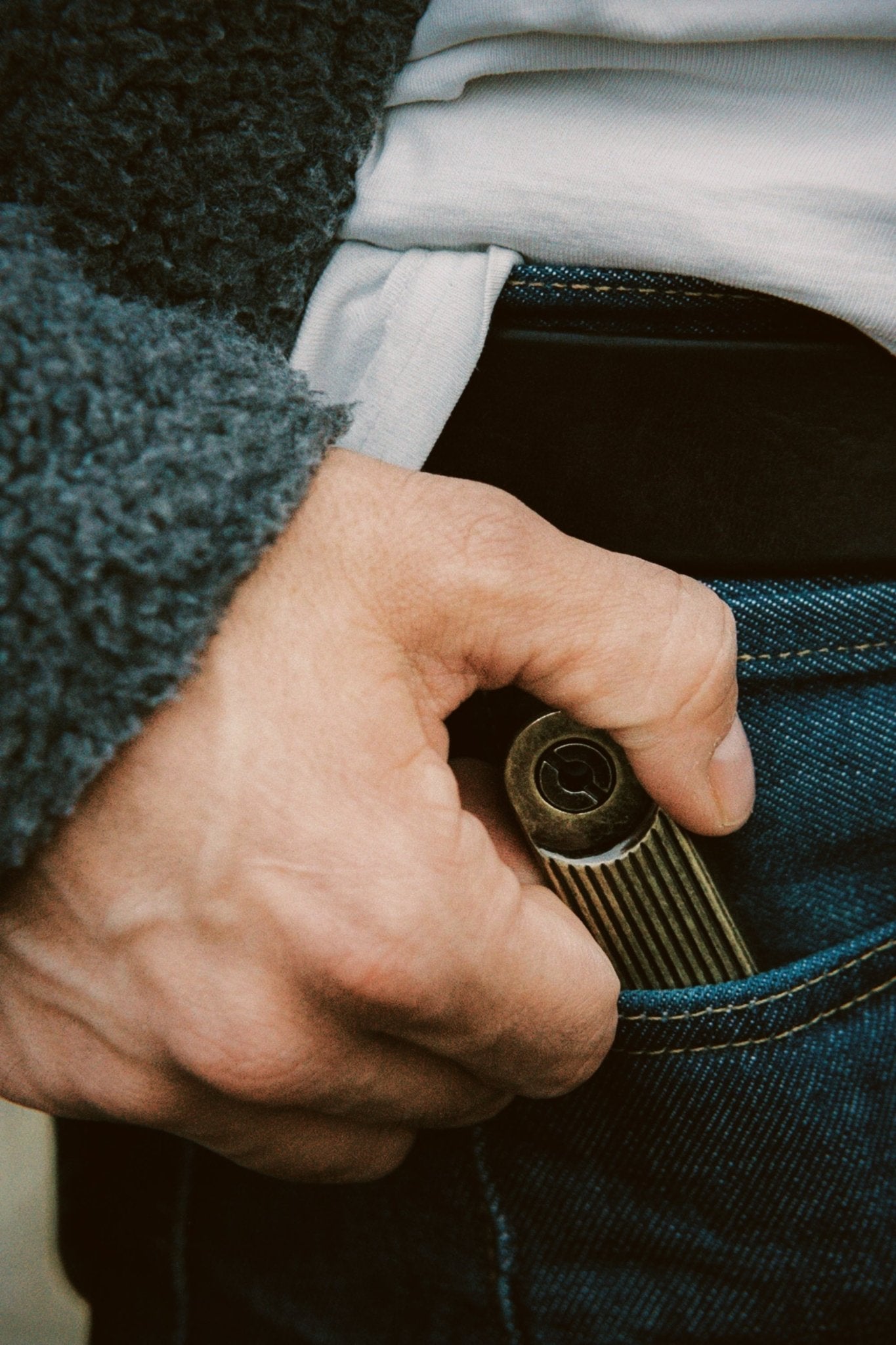 Hand holding a Barebones Arc-lighter in a pocket with a blurred background