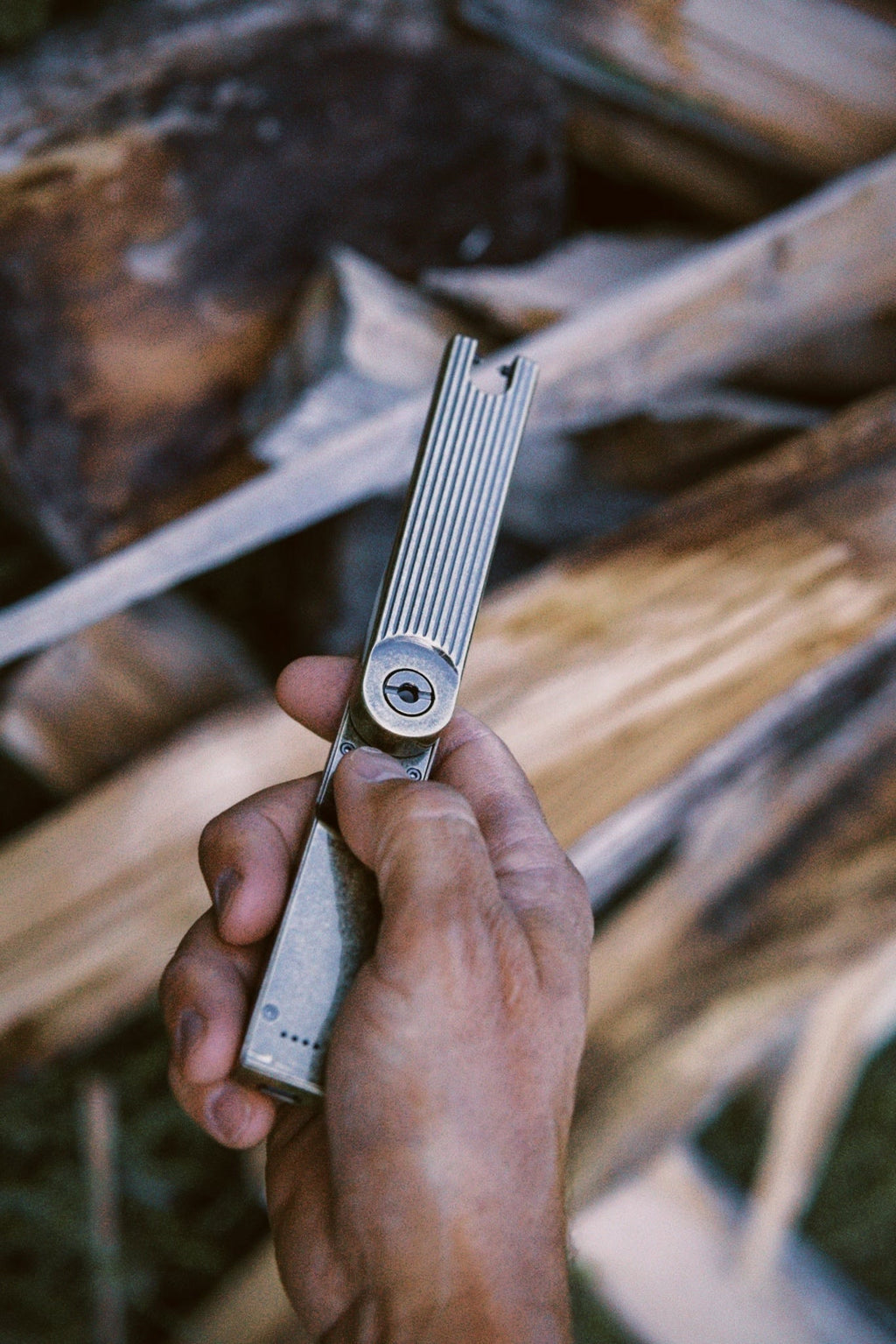 Hand holding a folding arc lighter against a wooden background