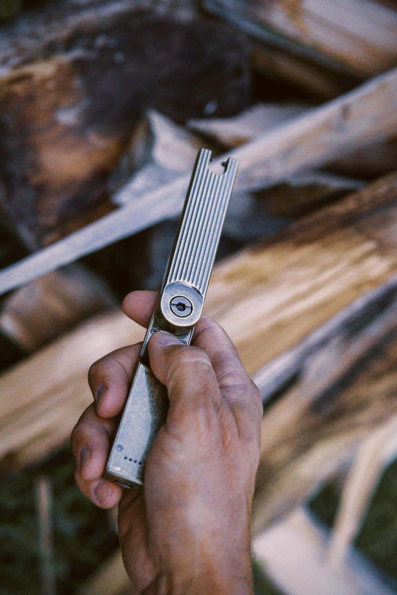 Hand holding a folding arc lighter against a wooden background
