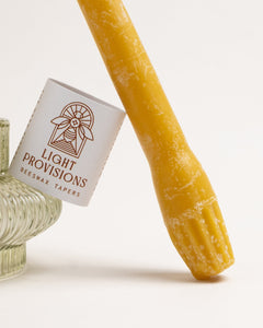 Detailed view of Light Provisions beeswax taper base and label, hand-dipped with textured ribbed foot design