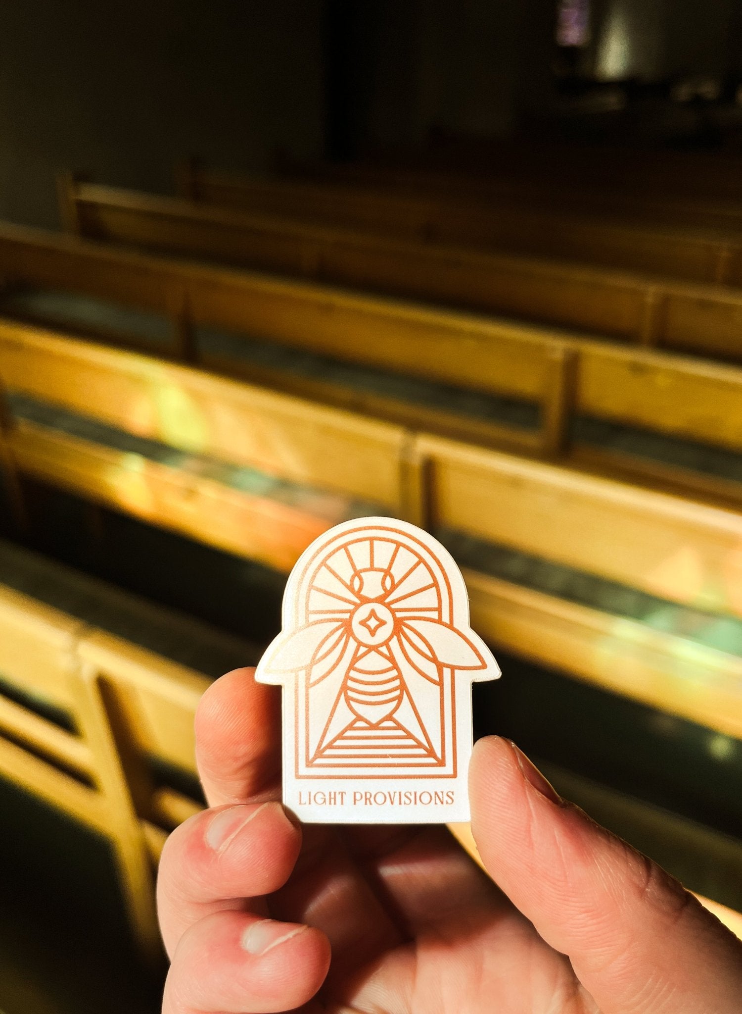 close up of a hand holding a sticker or a bee with a stained glass background in and old chirch.