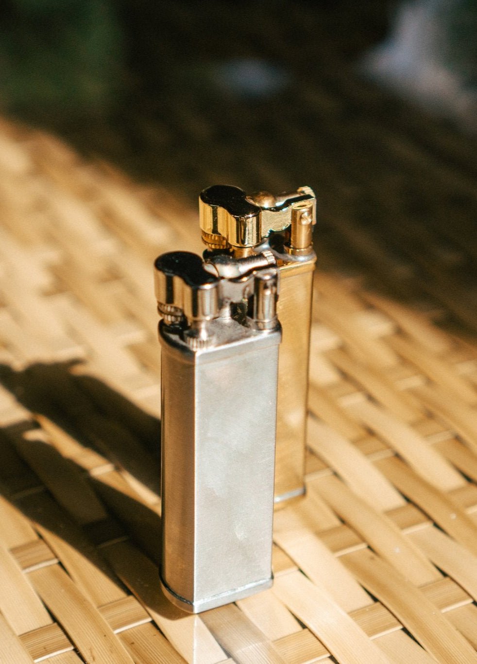 Bolbo Petrol Lighters by Tsubota Pearl standing upright on bamboo surface, Japanese craftsmanship in silver and brass finish.