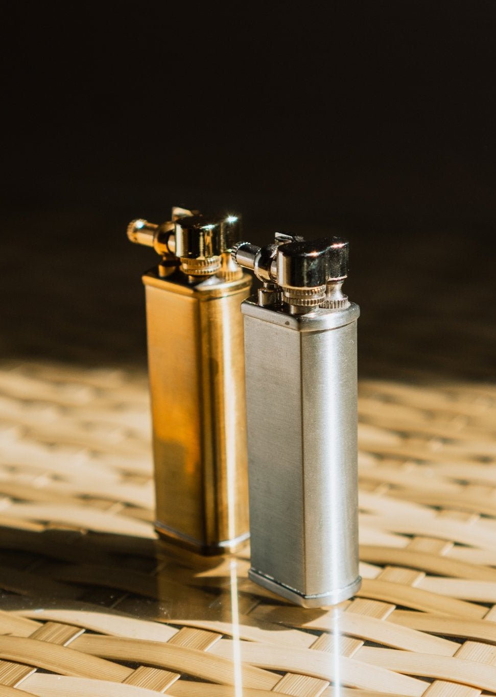Brass and steel Bolbo Petrol Lighters by Tsubota Pearl on woven surface, Japanese refillable design.