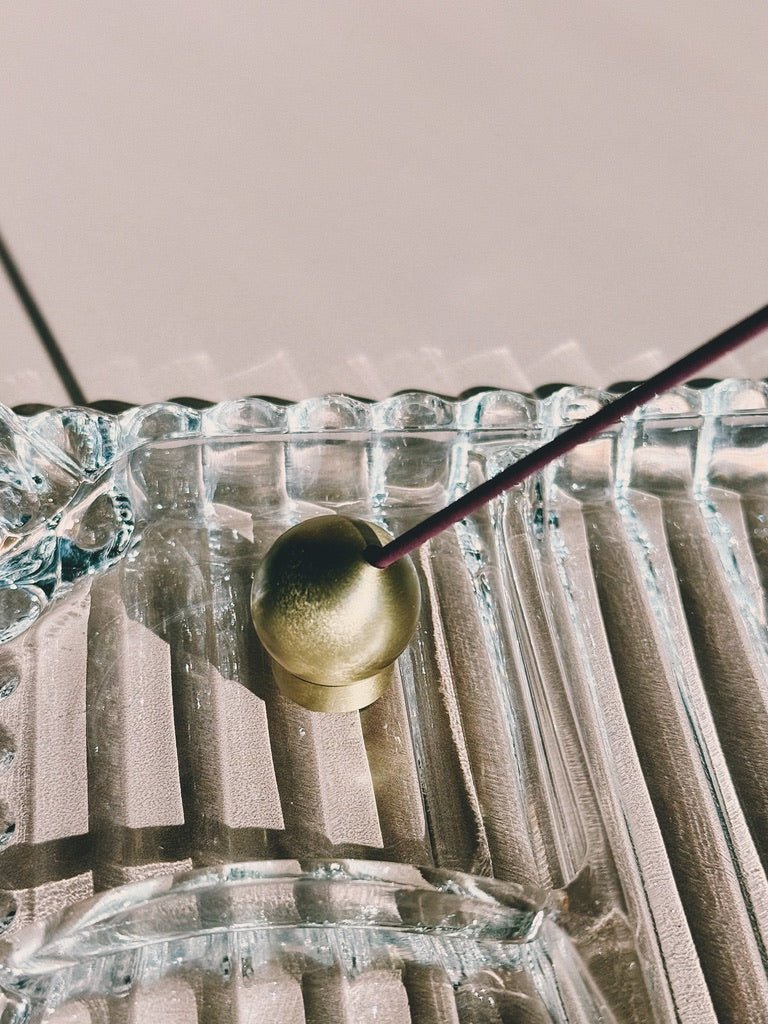 close up of sphere brass incense holder on vintage glass tray