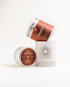 Campfire candle packaging with rust-colored tumbler box and ribbed glass holder, displayed together.
