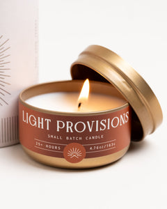 Close-up of Light Provisions Campfire travel tin candle burning, rust label, small batch, 25+ hour burn time.