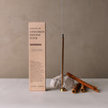 Hand-rolled cinnamon incense sticks displayed upright next to their minimalist packaging box on a neutral background