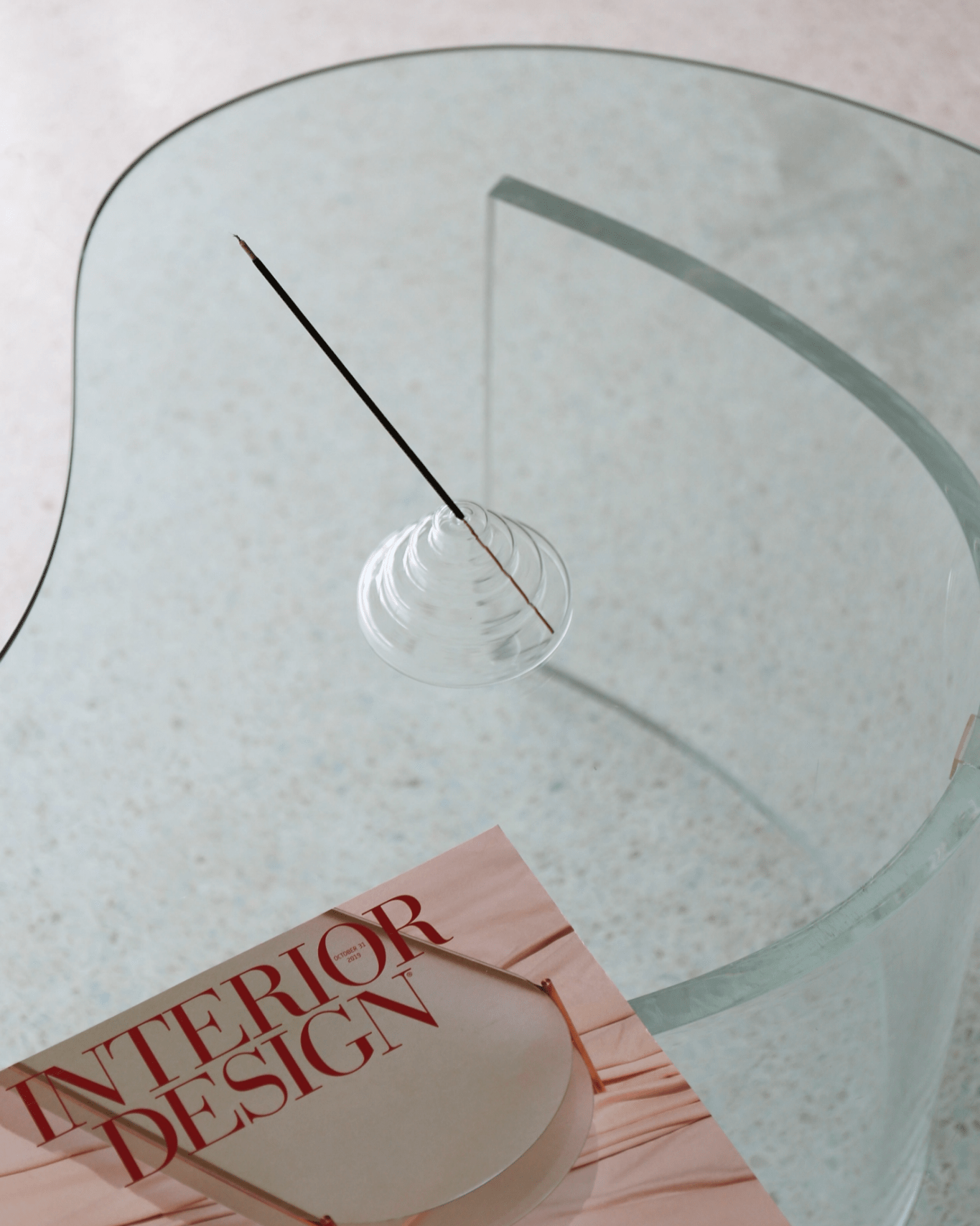 Clear meso incense holder on Glass table with a book titled 'Interior Design' on a light background