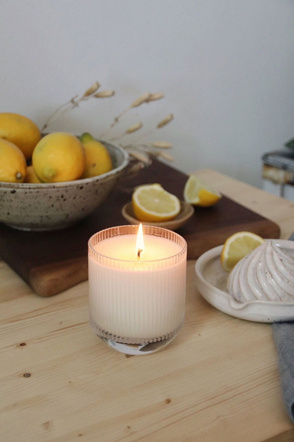 Cypress Lemon Candle in glass tumbler and travel tin styled with citrus fruit on counter