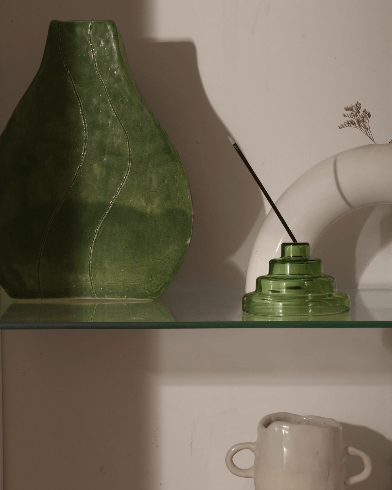Verde green Meso Glass Incense Holder holding incense stick styled on shelf with vases in warm golden light by Yield Design Co
