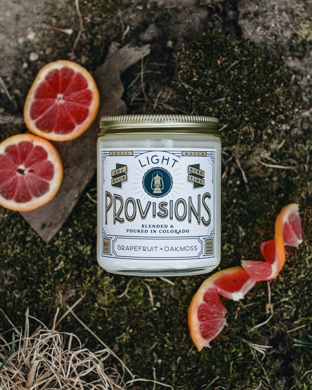 Can of 'Light Provisions'  grapefruit oakmoss candle on a natural background with sliced grapefruits