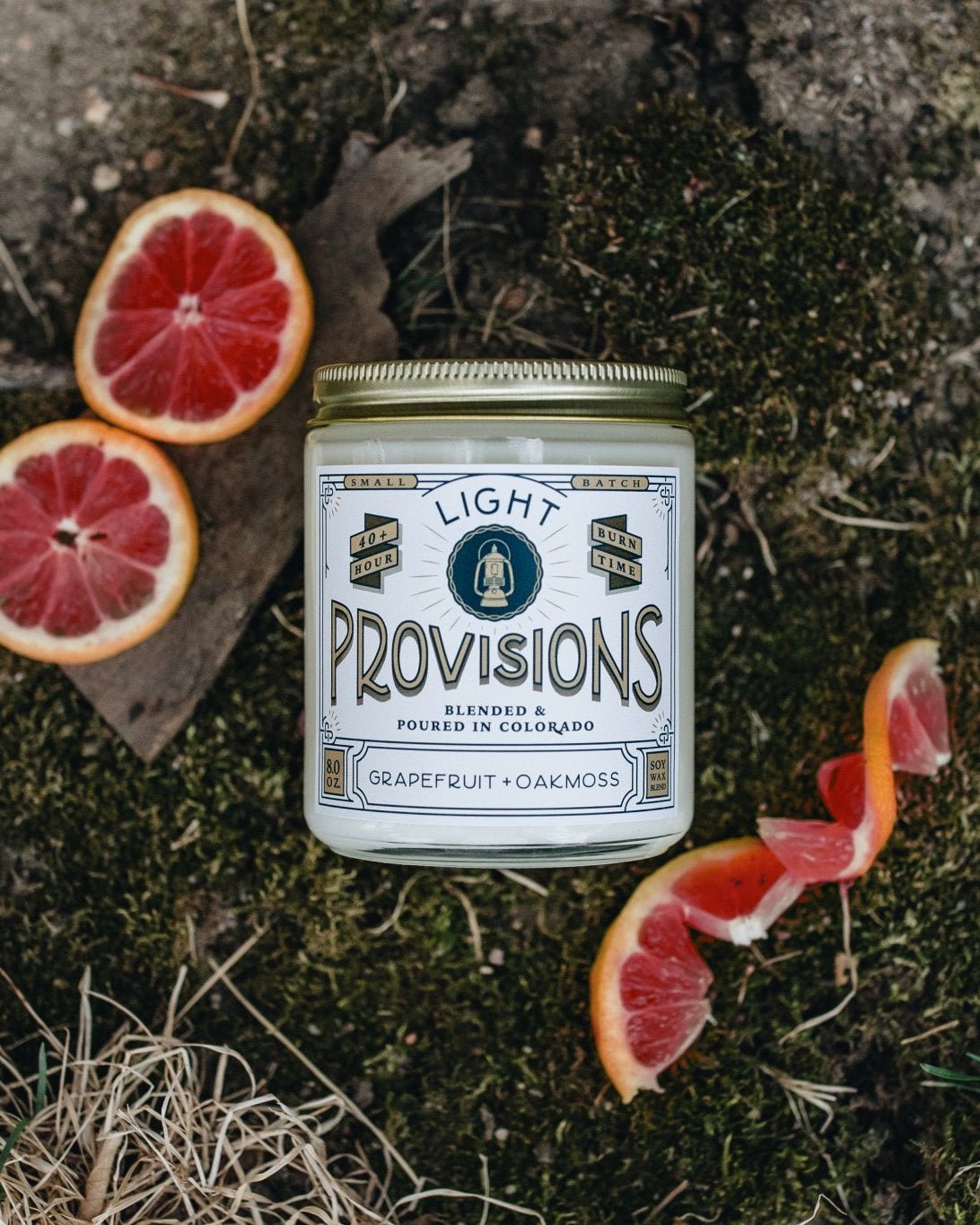 Can of 'Light Provisions'  grapefruit oakmoss candle on a natural background with sliced grapefruits