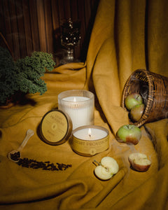 autumn scene featuring Light Provisions signature glass tumbler and travel tin on mustard backdrop with apples and greenery