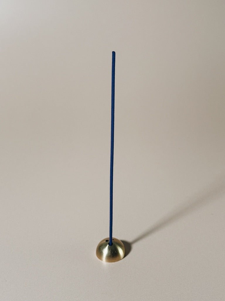 IYE agarwood Incense stick with brass "hemisphere" base on a plain background