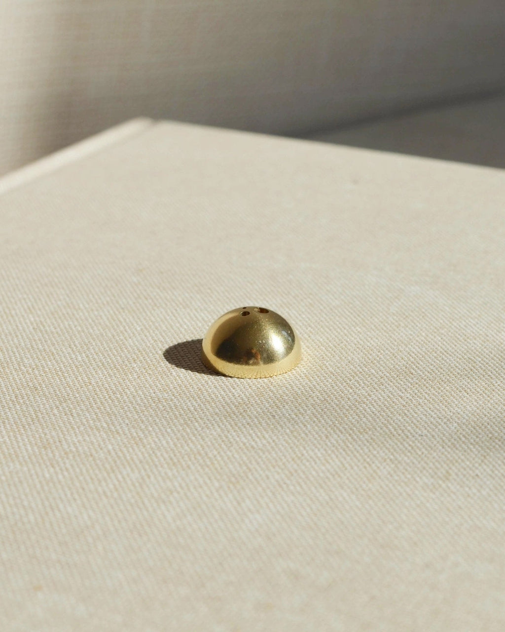 Brass hemisphere incense holder shown alone on a light surface, designed to hold multiple incense sizes.