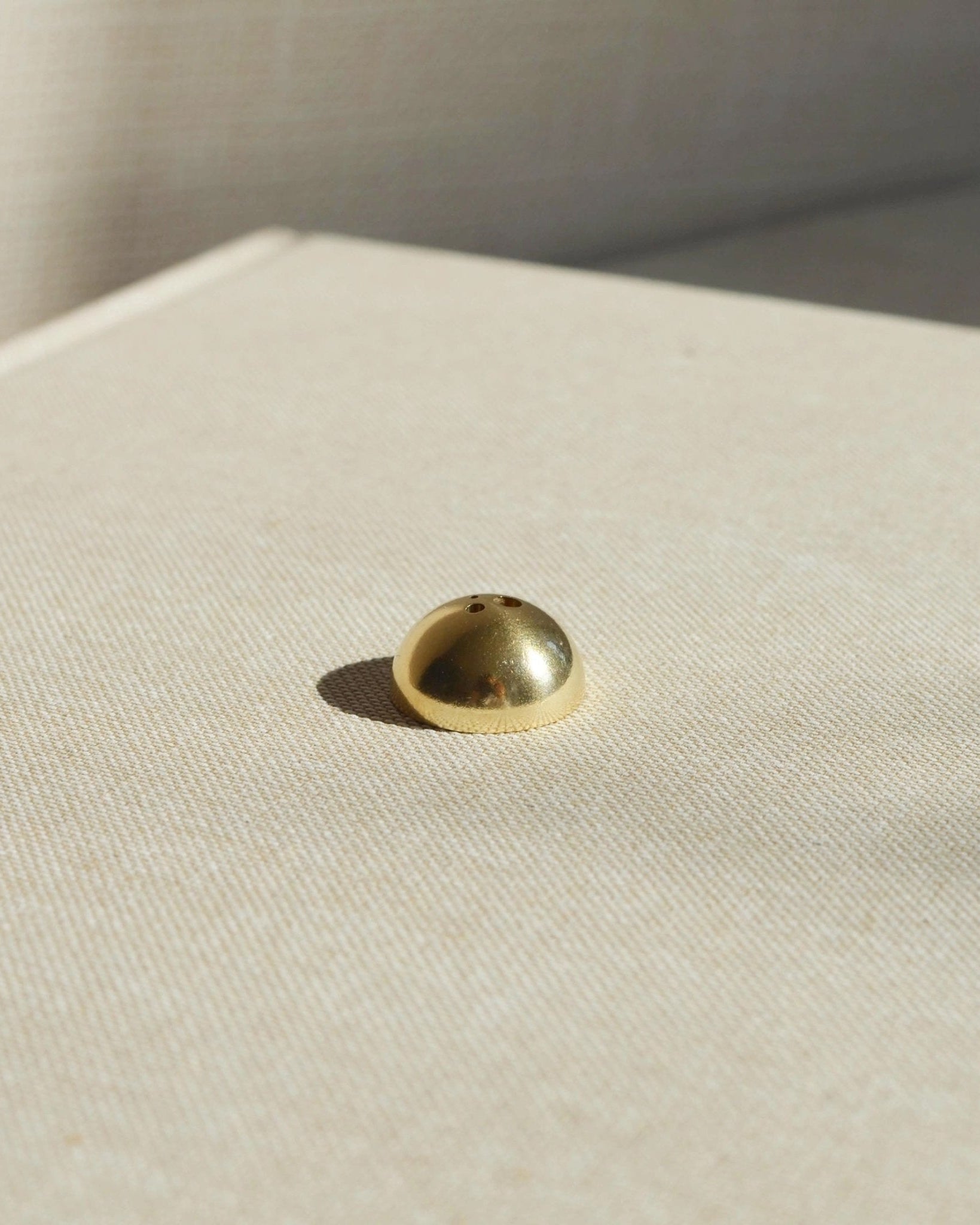 Brass hemisphere incense holder shown alone on a light surface, designed to hold multiple incense sizes.