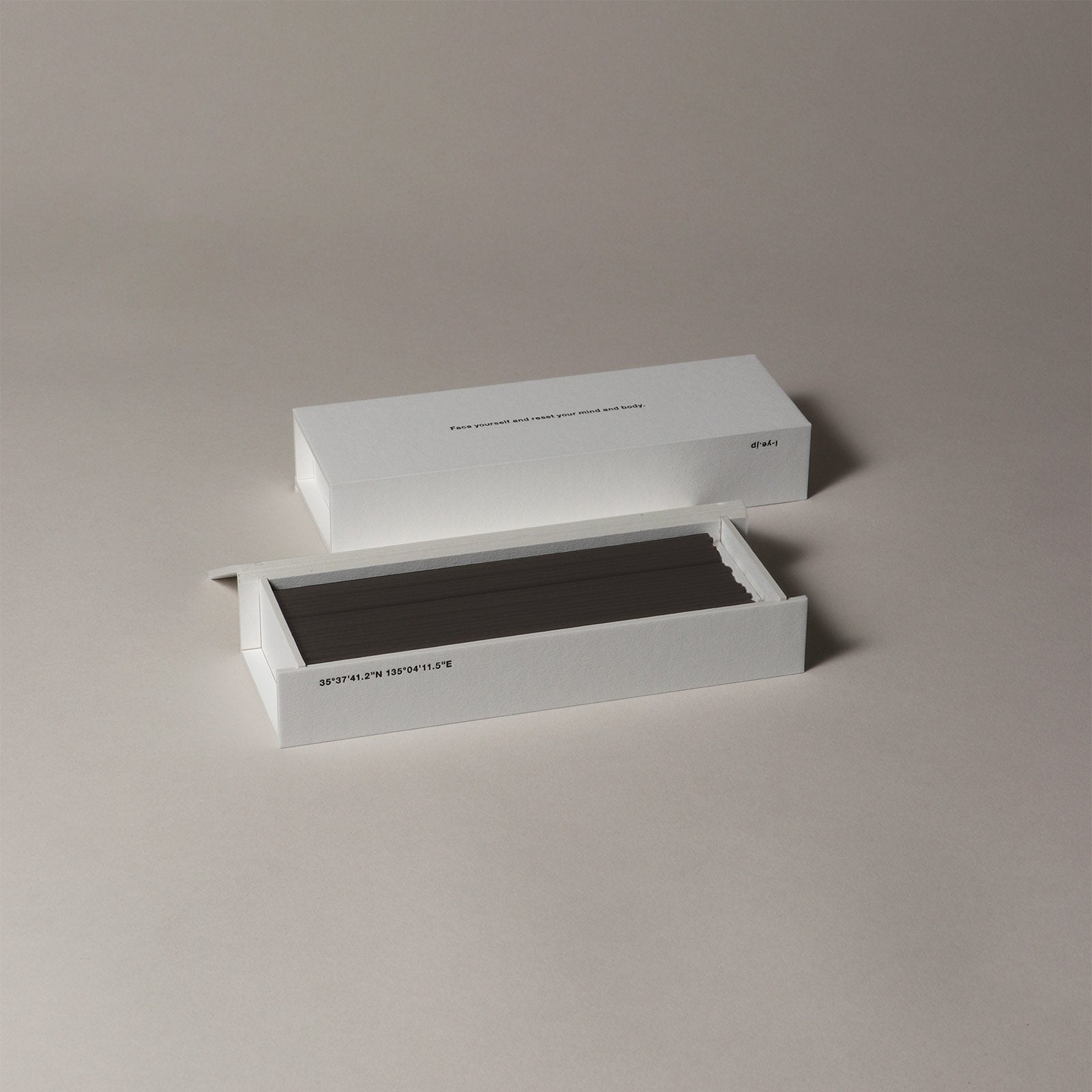 White rectangular IYE incense box with a black interior on a beige background