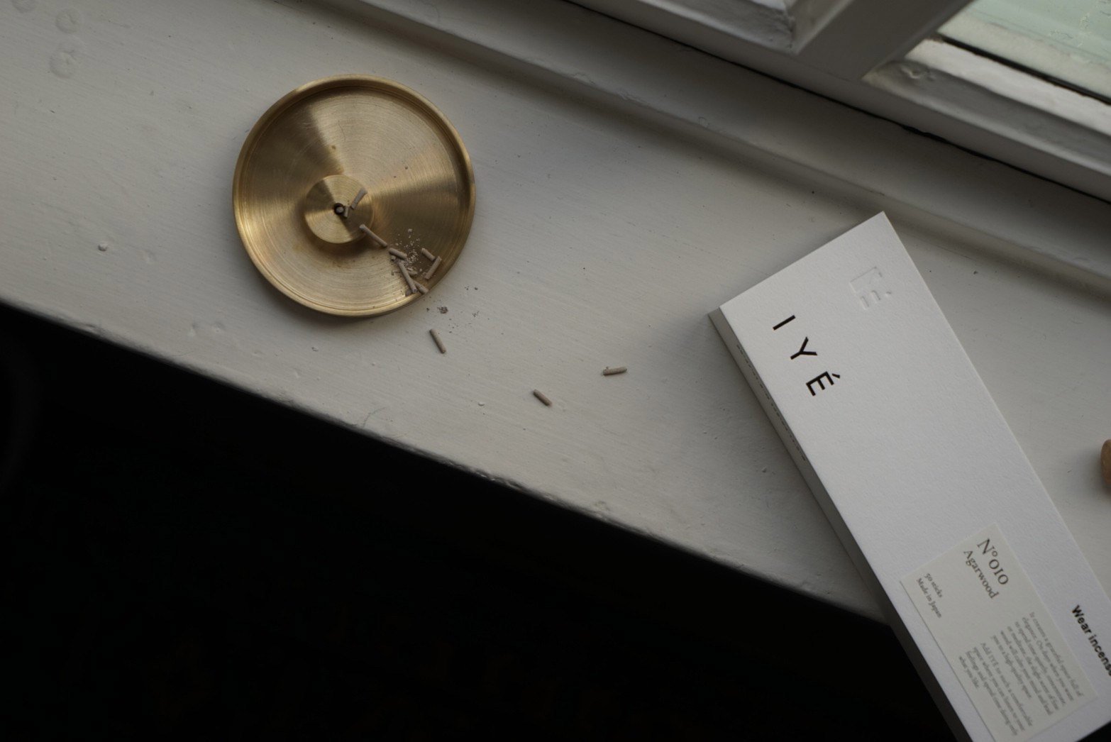 Brass incense holder dish and 'IYé' Incense agarwood box on a windowsill