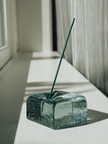 IYE recycled glass incense holder with a single green incense stick on a light surface.