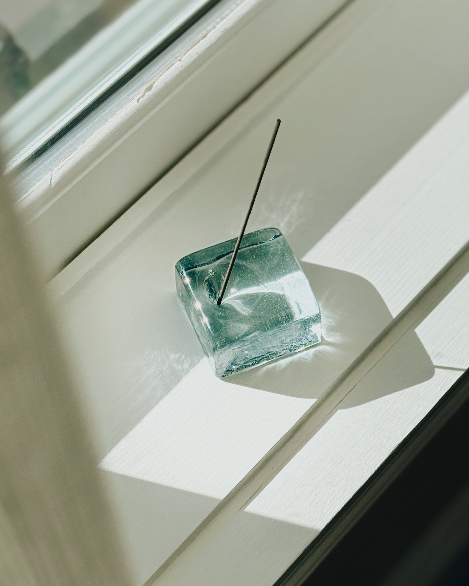 Top view of IYE recycled glass incense holder on window ledge in bright sunlight